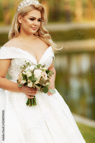 Young beautiful woman with long hair and blue eyes in long fabulous wedding dress in autumn park. Fairytale princess in the fall wood.