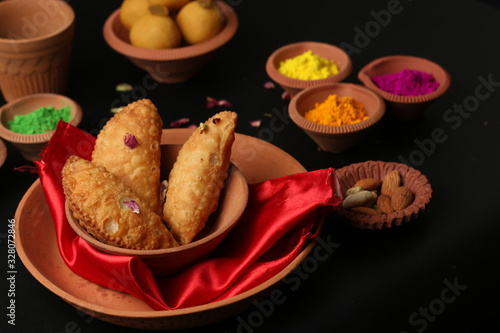 Popular Indian Sweet Besan Laddoo (gram flour sweet balls), Gujia or Karanji (coconut stuffed sweet bites) are well known indian Holi snack. (Holi Concept)