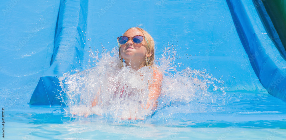 Child on water slide at aquapark. Summer holiday.