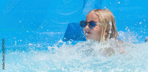 Child on water slide at aquapark. Summer holiday. © Guschenkova