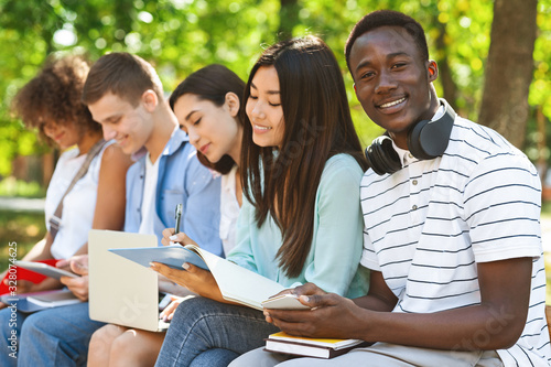 Smiling African American Student Guy Studying Outdoors With His University Friends