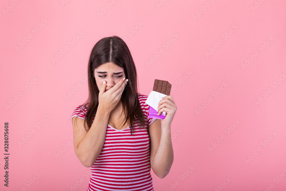 Portrait sad young woman tired of diet restrictions craving sweets chocolate isolated on pink wall background. Human face expression emotion. Nutrition concept. Feeling of guilt. Passion for chocolate Portrait sad young woman tired of diet restrictions craving sweets chocolate isolated on pink wall background. Human face expression emotion. Nutrition concept. Feeling of guilt. Passion for chocolate