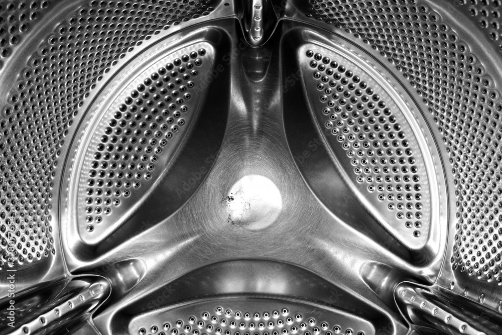Washing machine drum interior. Perforated stainless steel drum for automatic washing machine. Black and white, metallic background,texture
