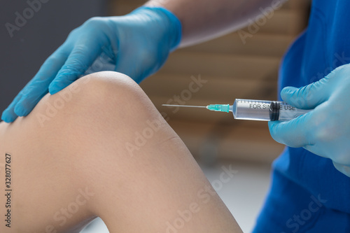 The doctor puts an injection into the patient's knee joint. A shot in the knee