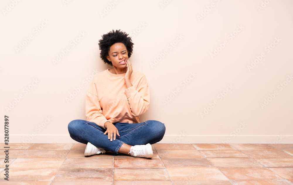 African american woman sitting on the floor with toothache African american woman sitting on the floor with toothache