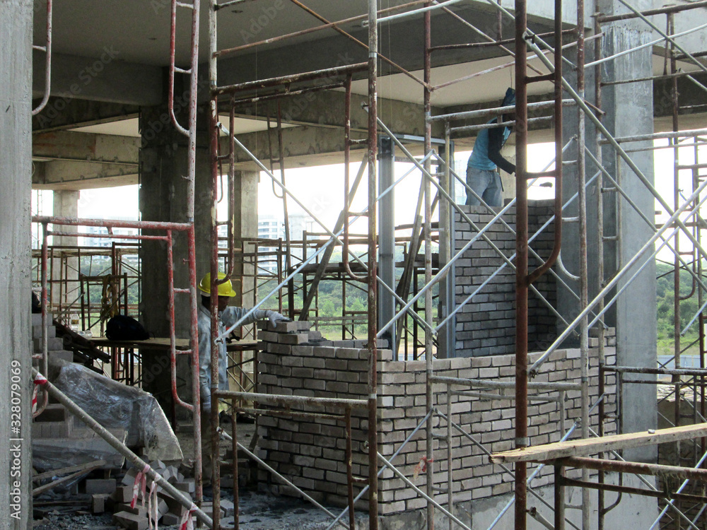 Brickwork by construction workers at the construction site. Workers laying brick and stacked it together using mortar to form the wall. 