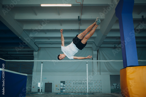 Young male acrobat jumping on a trampoline