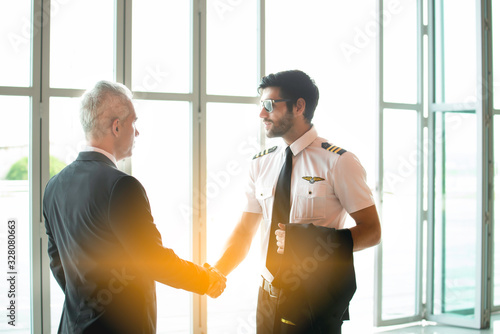 Young pilot man in uniform talking with business man about aviation businessn,startup,business team,people,Young caucasian pilot and businessman talking about Aviation business at the airport terminal photo