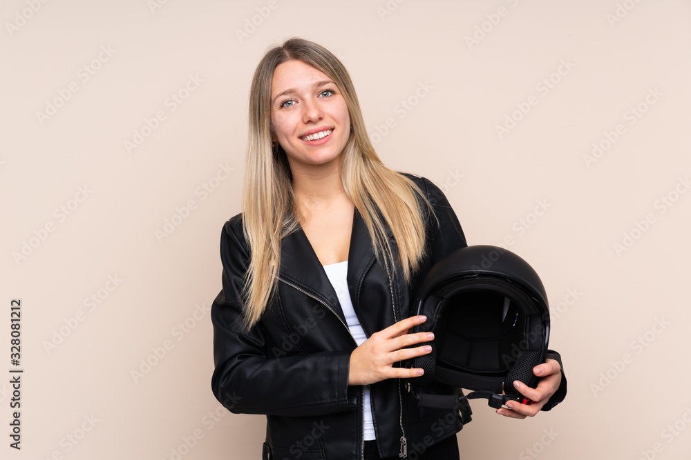 Young blonde woman with a motorcycle helmet over isolated background laughing Young blonde woman with a motorcycle helmet over isolated background laughing