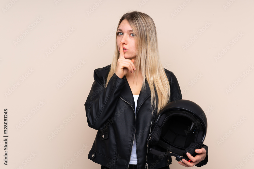 Young blonde woman with a motorcycle helmet over isolated background doing silence gesture Young blonde woman with a motorcycle helmet over isolated background doing silence gesture