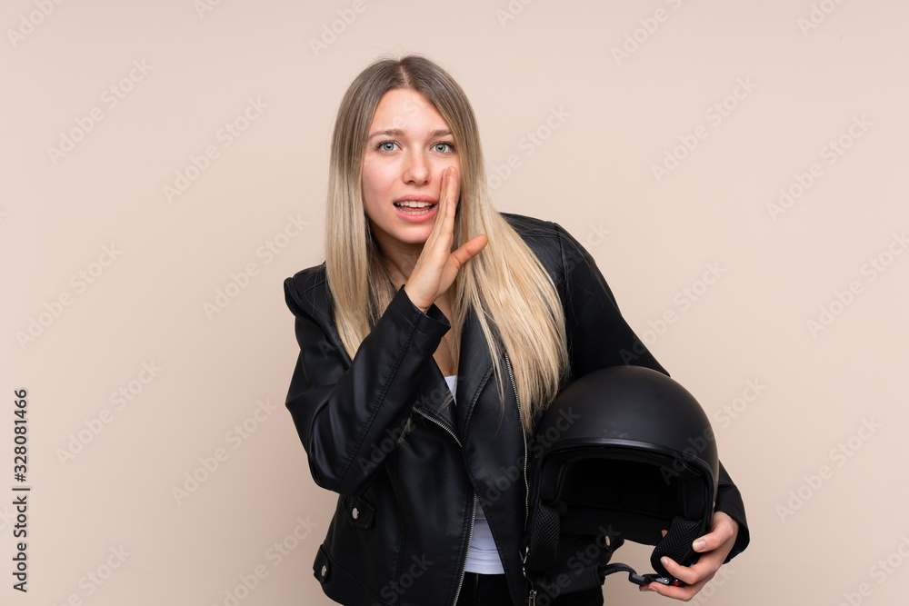 Young blonde woman with a motorcycle helmet over isolated background whispering something Young blonde woman with a motorcycle helmet over isolated background whispering something