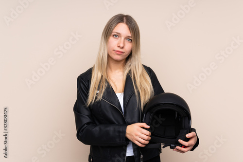 Young blonde woman with a motorcycle helmet over isolated background keeping arms crossed © luismolinero