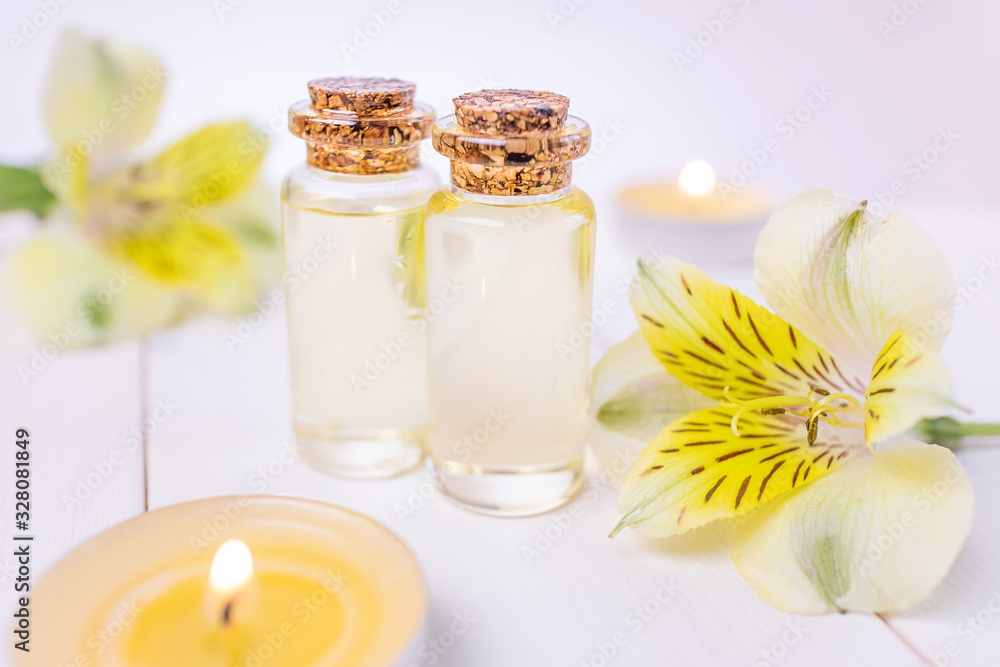 The concept of aromatherapy, spa. Bottles with floral essential oil on a white wooden background. Nearby is a yellow flower, candles. Cozy still life in bright colors. The concept of aromatherapy, spa. Bottles with floral essential oil on a white wooden background. Nearby is a yellow flower, candles. Cozy still life in bright colors.