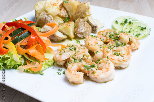 Garlic shrimp, bathed in garlic sauce, accompanied by potatoes and vegetables