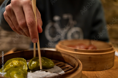 Man eating dim sum, Asian food, using chopsticks. With a beard and a jumper. Lifestyle.
