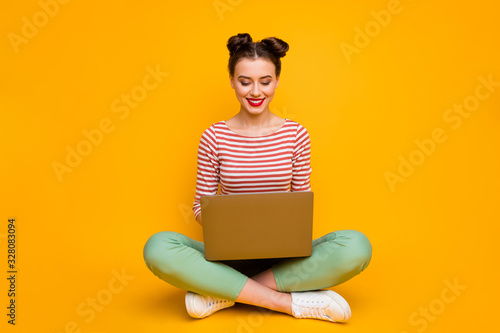 Full length photo of attractive lady sit floor legs crossed hold notebook writing essay work report wear striped red white shirt green pants shoes isolated yellow color background