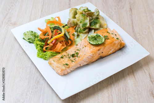 Salmon with garlic and lemon, accompanied by sauteed vegetables and spicy potatoes