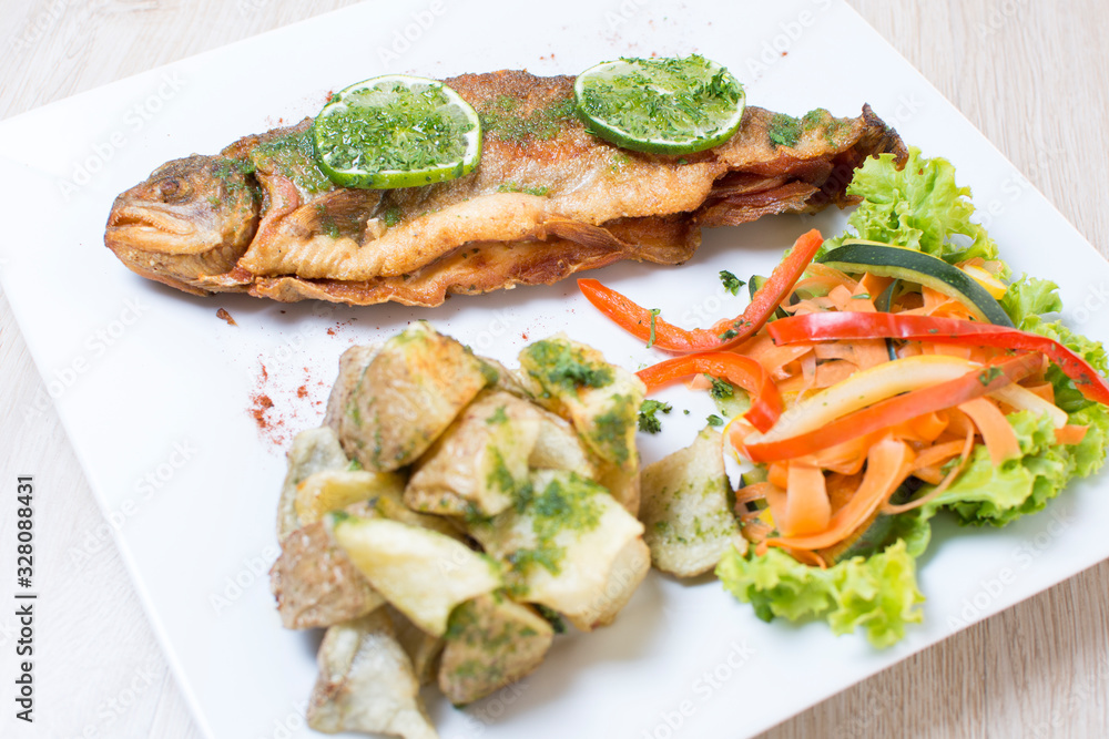 Baked trout, stuffed with ham and cheese, accompanied by spicy potatoes and vegetables