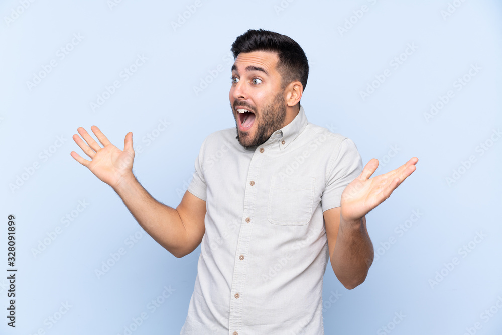 Fototapeta premium Young handsome man with beard over isolated blue background with surprise facial expression