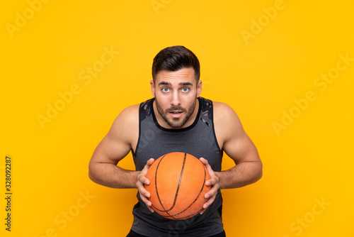 Man over isolated yellow background playing basketball