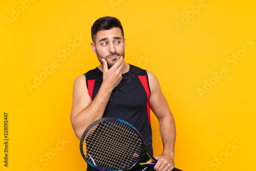 Man over isolated yellow background playing tennis and thinking © luismolinero