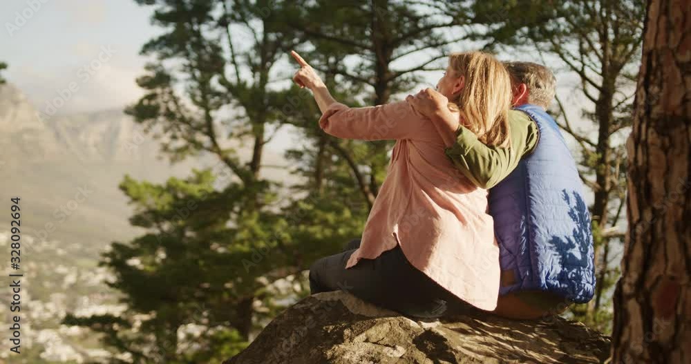 Active senior couple sitting on rock in forest Active senior couple sitting on rock in forest
