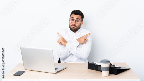 Young businessman in a workplace pointing to the laterals having doubts