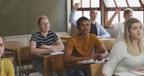 Student raising his hand in high school class photo