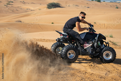 Fototapeta Naklejka Na Ścianę i Meble -  Muscular Man Riding Atv In the Desert