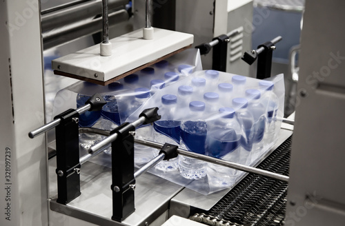 Shrink film wrapping machine for package bottle of water. Food industry	