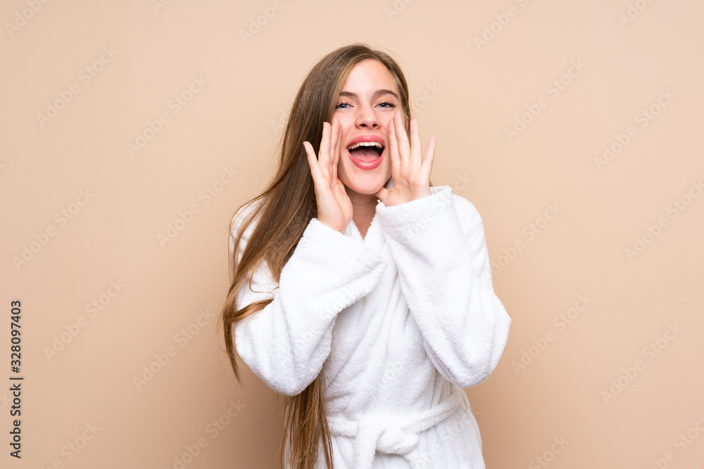 Teenager girl in a bathrobe over isolated background shouting with mouth wide open Teenager girl in a bathrobe over isolated background shouting with mouth wide open