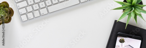 A desk in the office. View from above. White empty copy space. Imac computer, smartphone, notebook and succulents. Mockup. Panorama