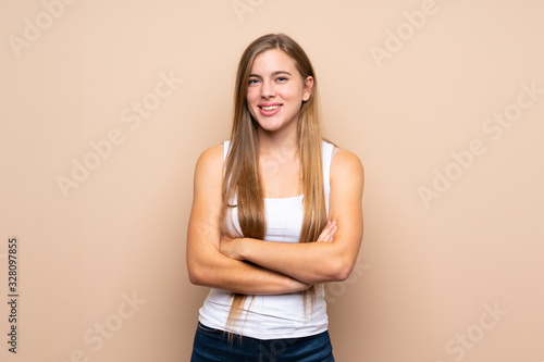 Teenager blonde girl over isolated background keeping the arms crossed in frontal position