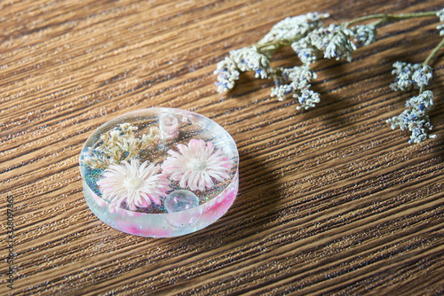 Pink dried flower with colorful glitter in accesory hand-made resin on wooden background