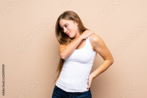 Teenager blonde girl over isolated background suffering from pain in shoulder for having made an effort