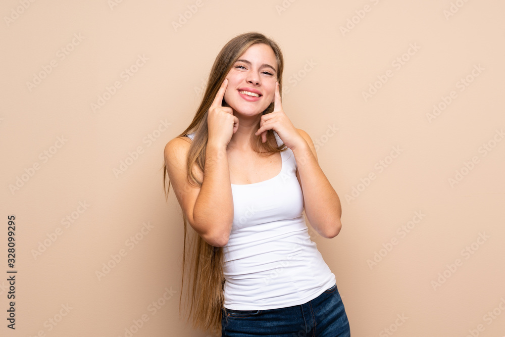 Fototapeta premium Teenager blonde girl over isolated background smiling with a happy and pleasant expression
