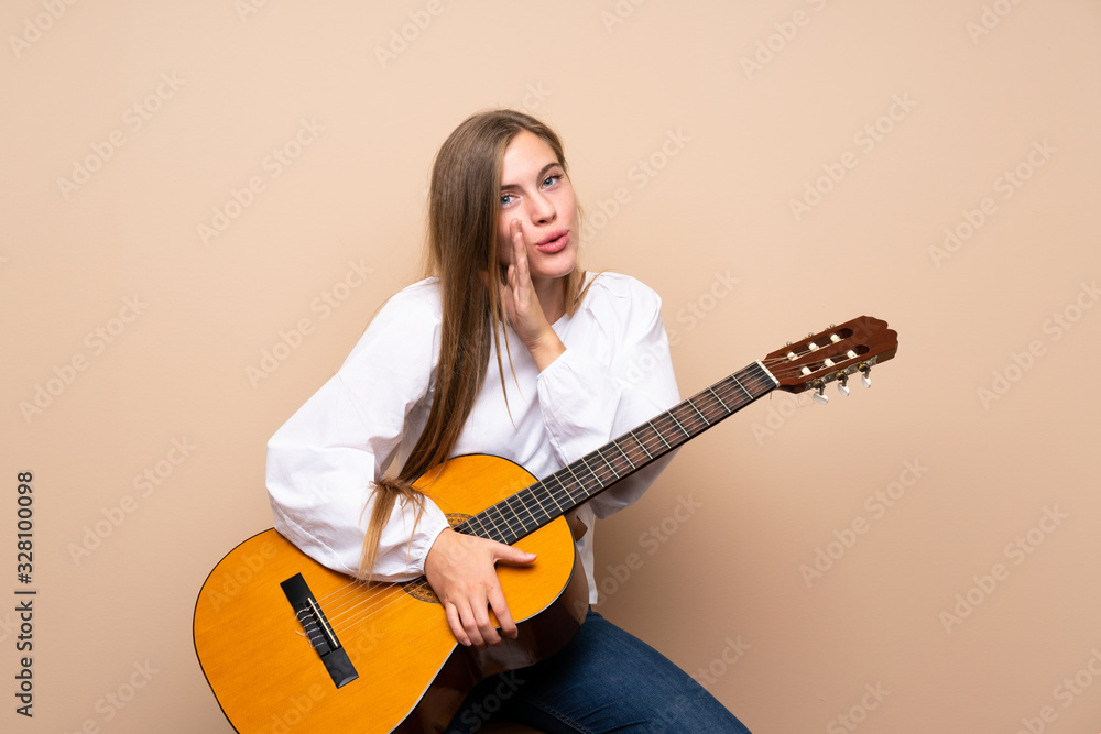 Teenager girl with guitar over isolated background whispering something Teenager girl with guitar over isolated background whispering something