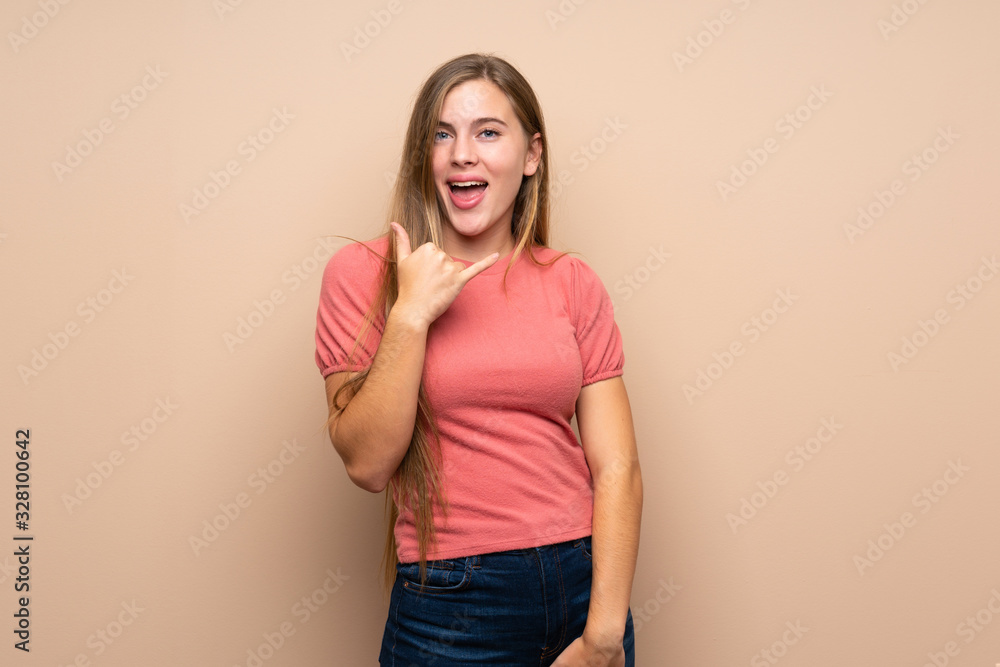 Teenager blonde girl over isolated background making phone gesture Teenager blonde girl over isolated background making phone gesture