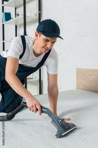 Cuadro en lienzo happy cleaner in cap removing dust on mattress with vacuum cleaner