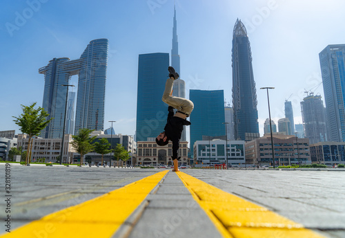 Bild auf Leinwand Acrobat keep balance one the hands with blurred Dubai cityscape