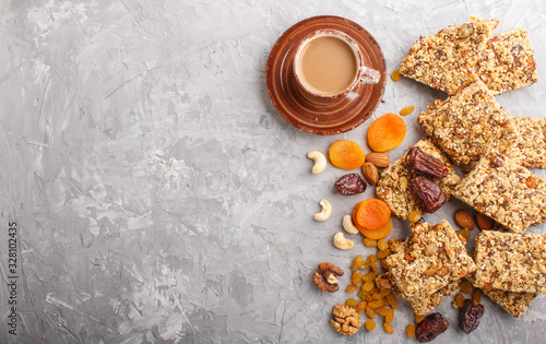 Homemade granola from oat flakes, dates, dried apricots, raisins, nuts with a cup of coffee on a gray concrete background. Top view.