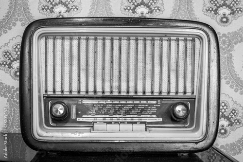 March 1, 2020 - Rome, Italy - Telefunken Mignonette, an old transistor radio, with knobs and buttons for manual tuning. In the background a vintage wallpaper. Ancient object, worn and ruined by time. photo