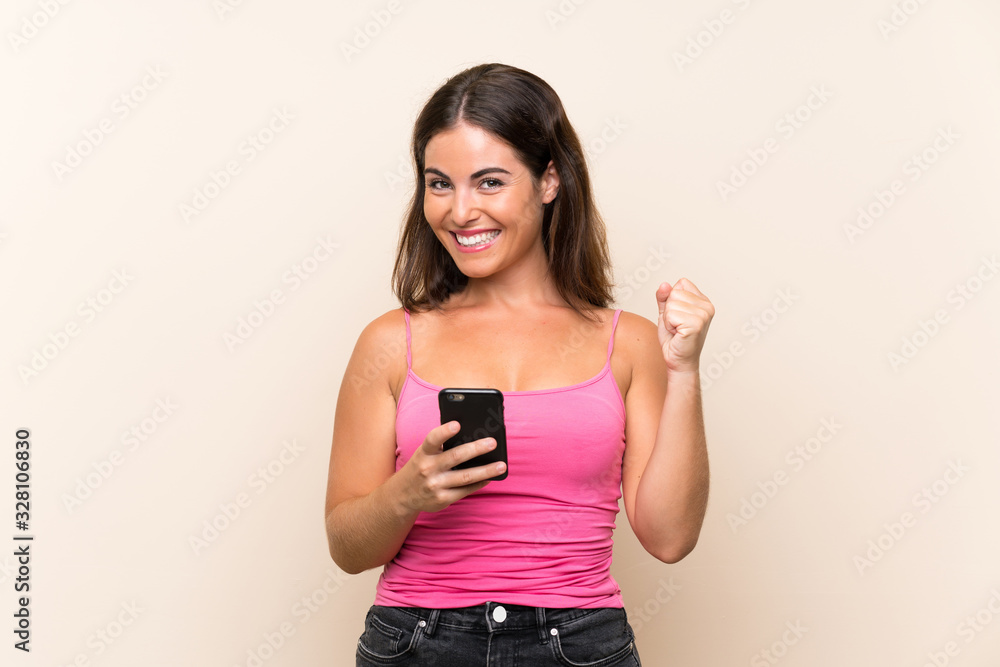 Young woman over isolated white background with phone in victory position Young woman over isolated white background with phone in victory position