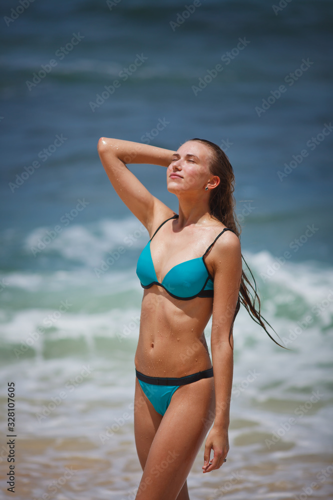 girl in a blue swimsuit walks on a tropical beach