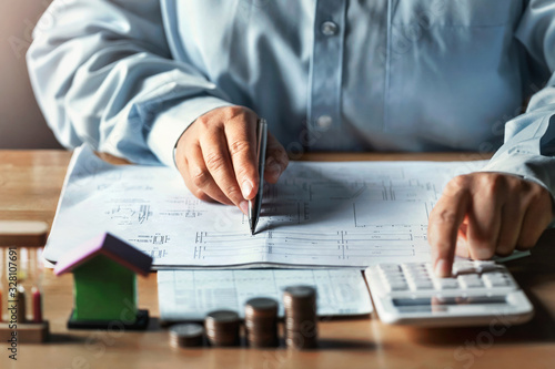 businessman working on desk office with using a calculator to calculate finance accounting concept