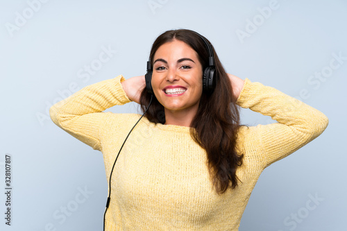 Young woman listening music with a mobile over isolated blue wall