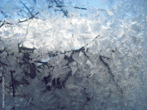 Texture of frosty patterns. Winter frosty patterns on the glass. New Year and Christmas abstract icy snowy background with real ice crystals macro in cold blue tones. Natural Snowflakes. Soft focus