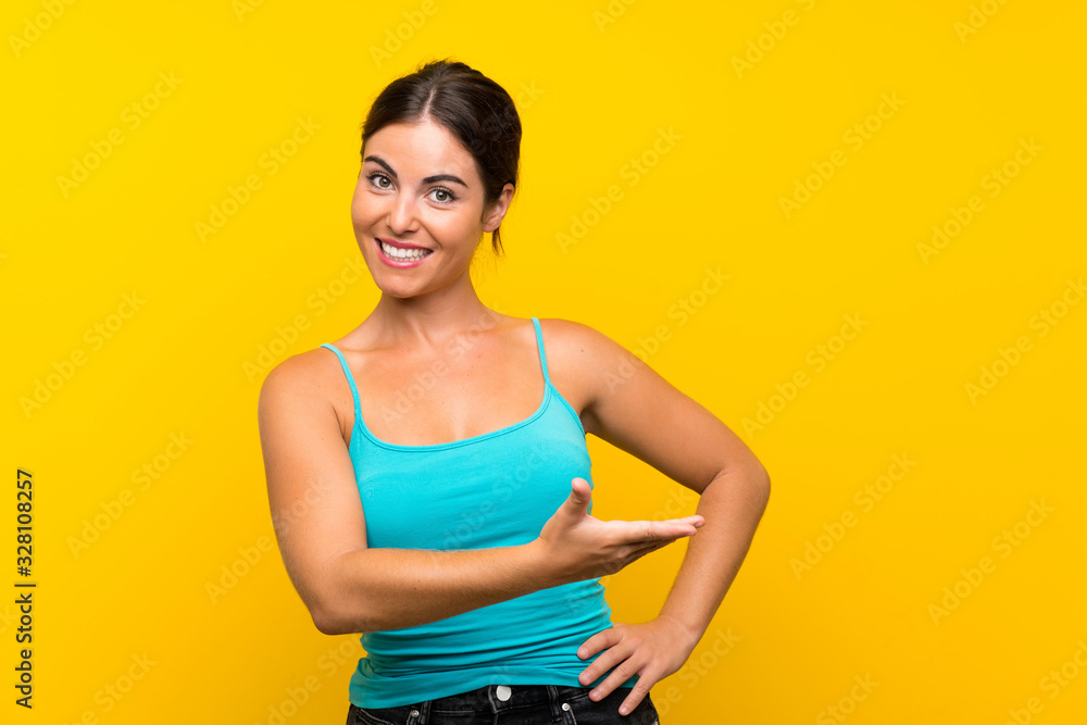 Young woman over isolated yellow background extending hands to the side for inviting to come Young woman over isolated yellow background extending hands to the side for inviting to come