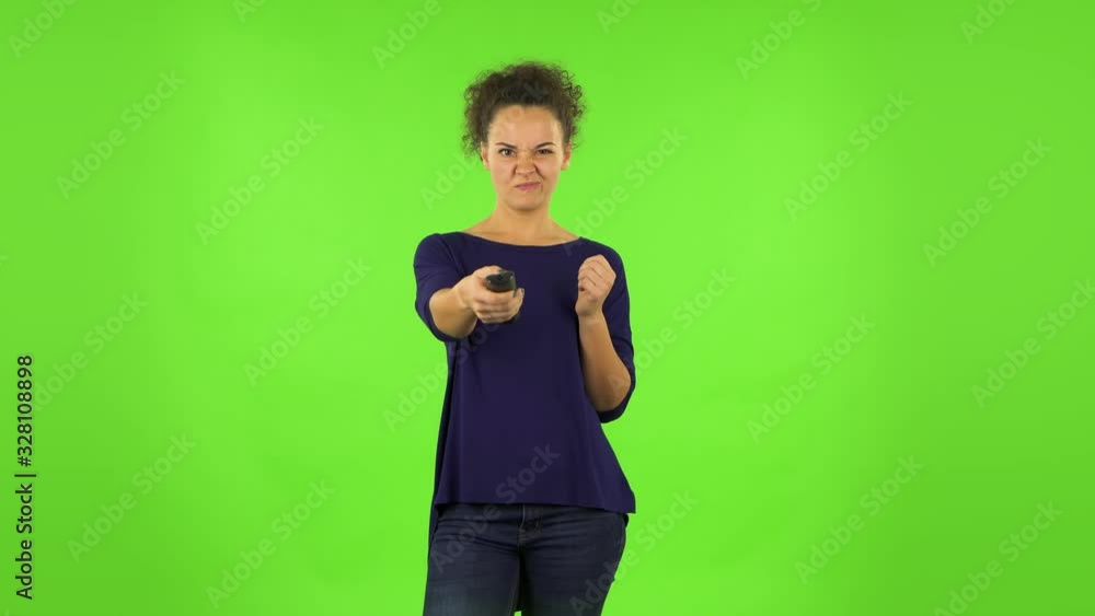 Curly woman with TV remote in her hand, switching on TV. Green screen Curly woman with TV remote in her hand, switching on TV. Green screen