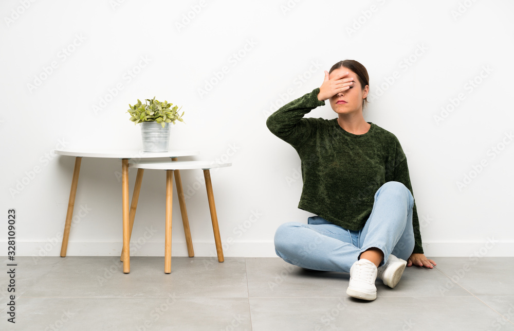 Young woman sitting on the floor covering eyes by hands Young woman sitting on the floor covering eyes by hands